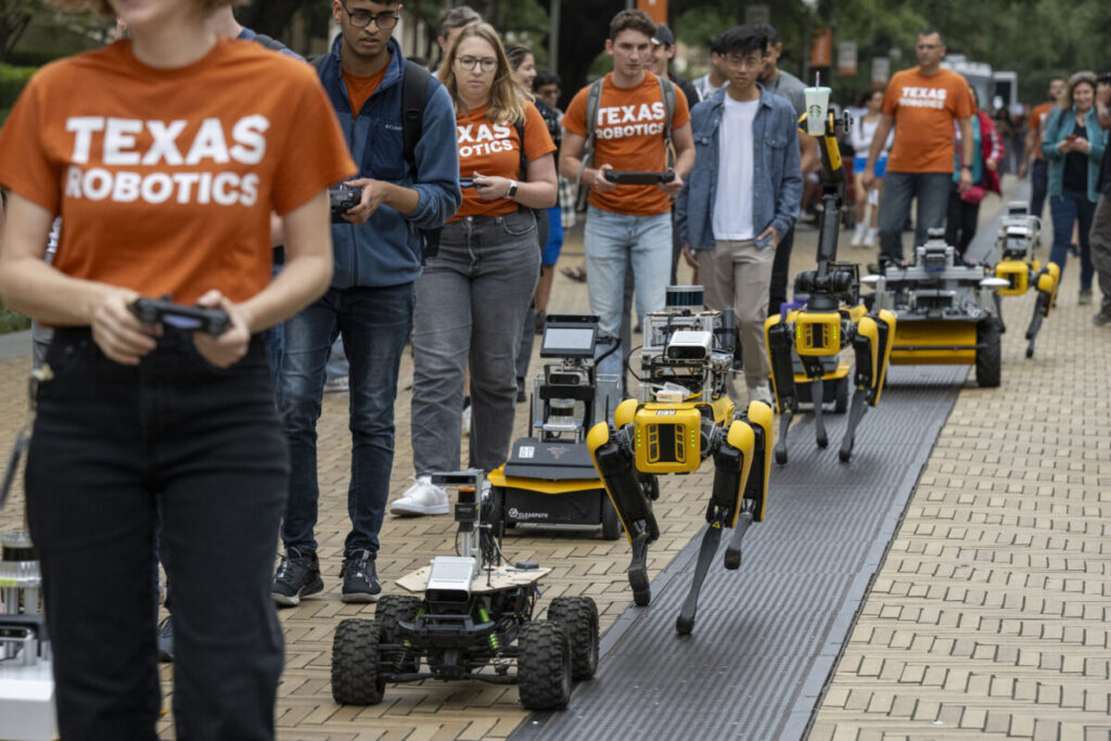 Texas Robotics students and their robots in a parade down Speedway on UT campus