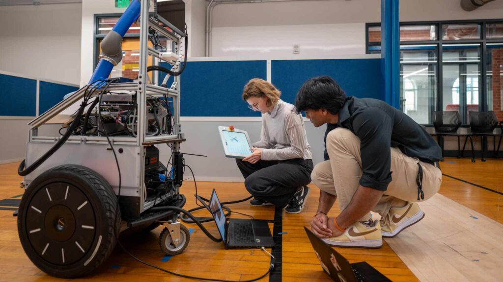 student and professor in Robotics lab working to control a robot